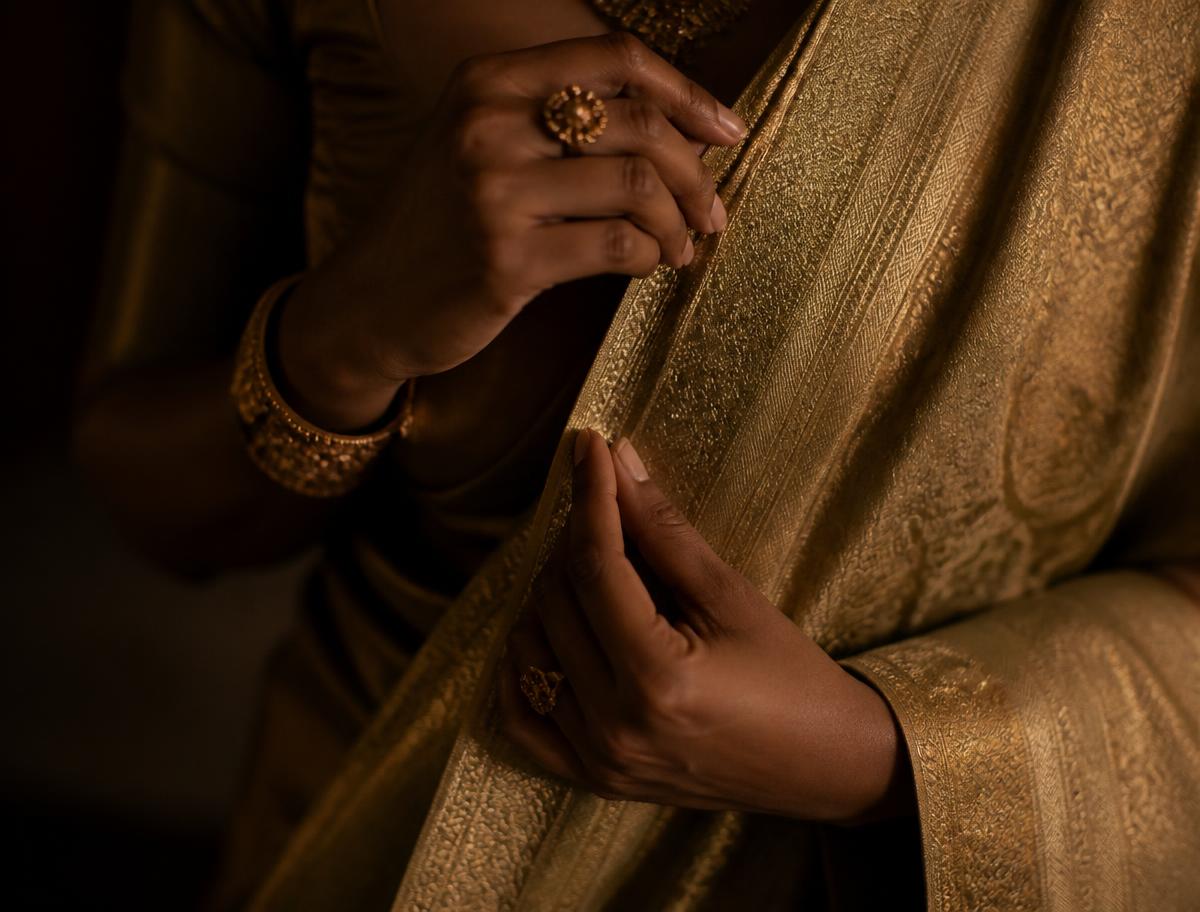 Close detail of hands adjusting a gold zari pallu